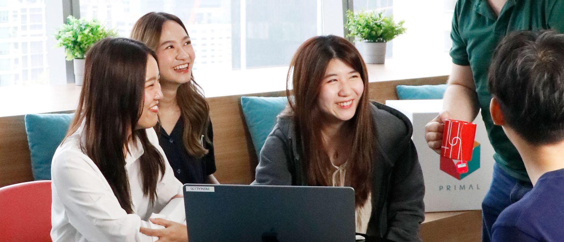 ทีมงานสี่คนกำลังประชุมและดูหน้าจอแล็ปท็อปร่วมกันในออฟฟิศ
