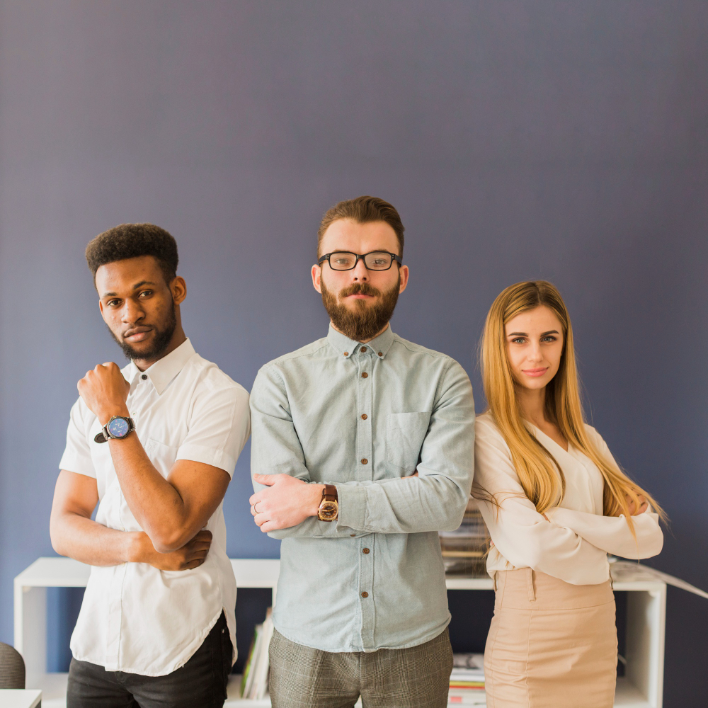Three colleagues standing with folded arms in an office
