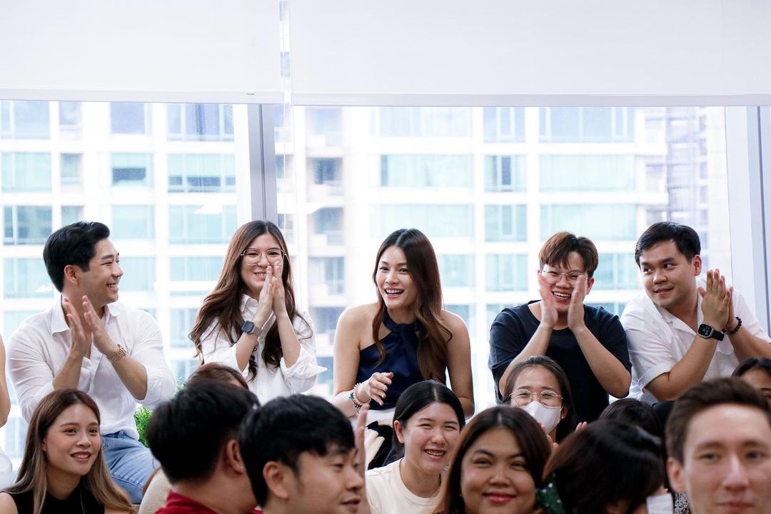 Primal staff applauding a colleague in a meeting room beside glass windows