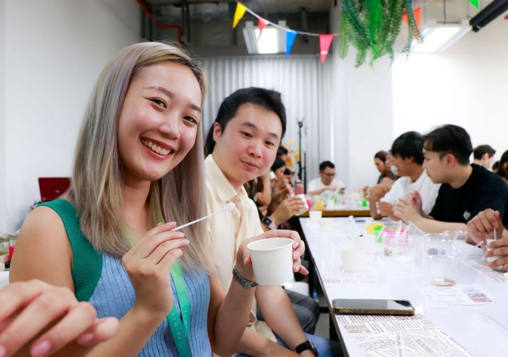 Two employees smiling at the camera during a workshop at a long table