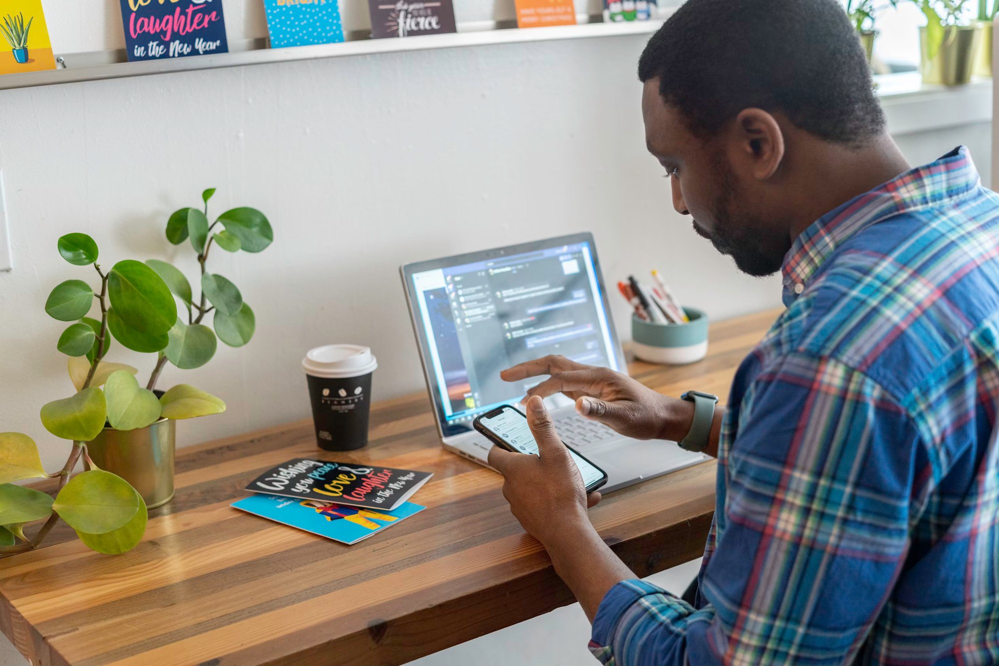 Person checking a message on a phone beside an open laptop
