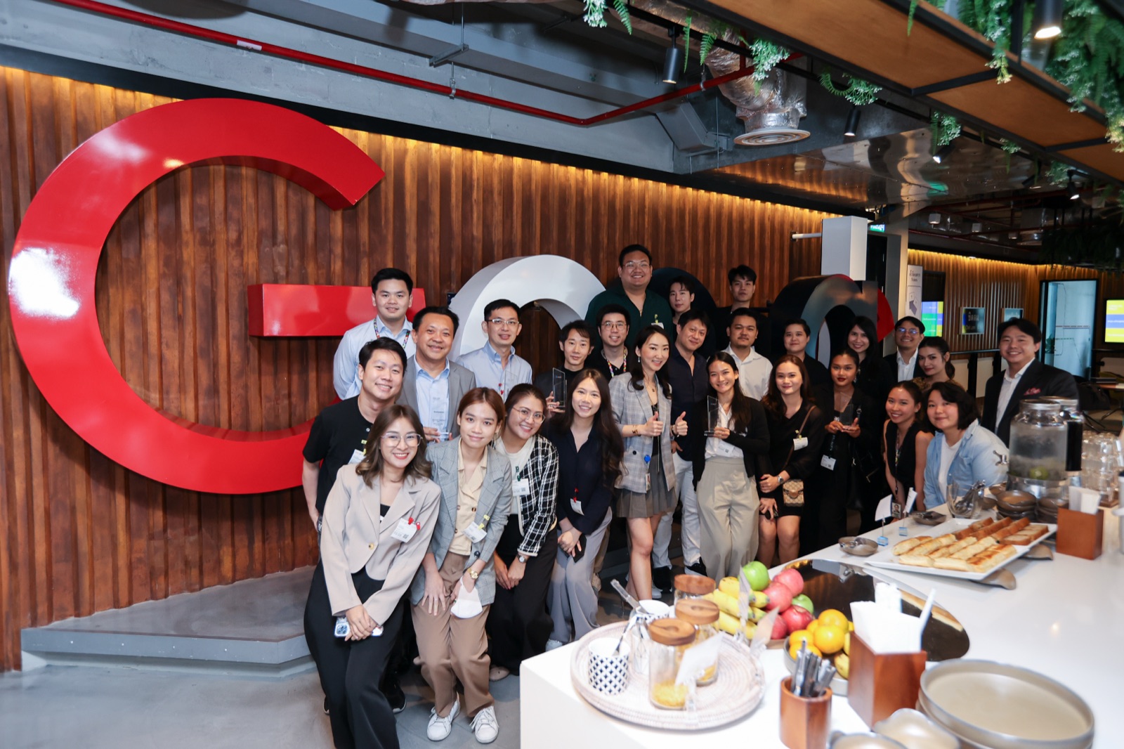 The Primal team posing for a group photo in front of a large red letter G at a company event