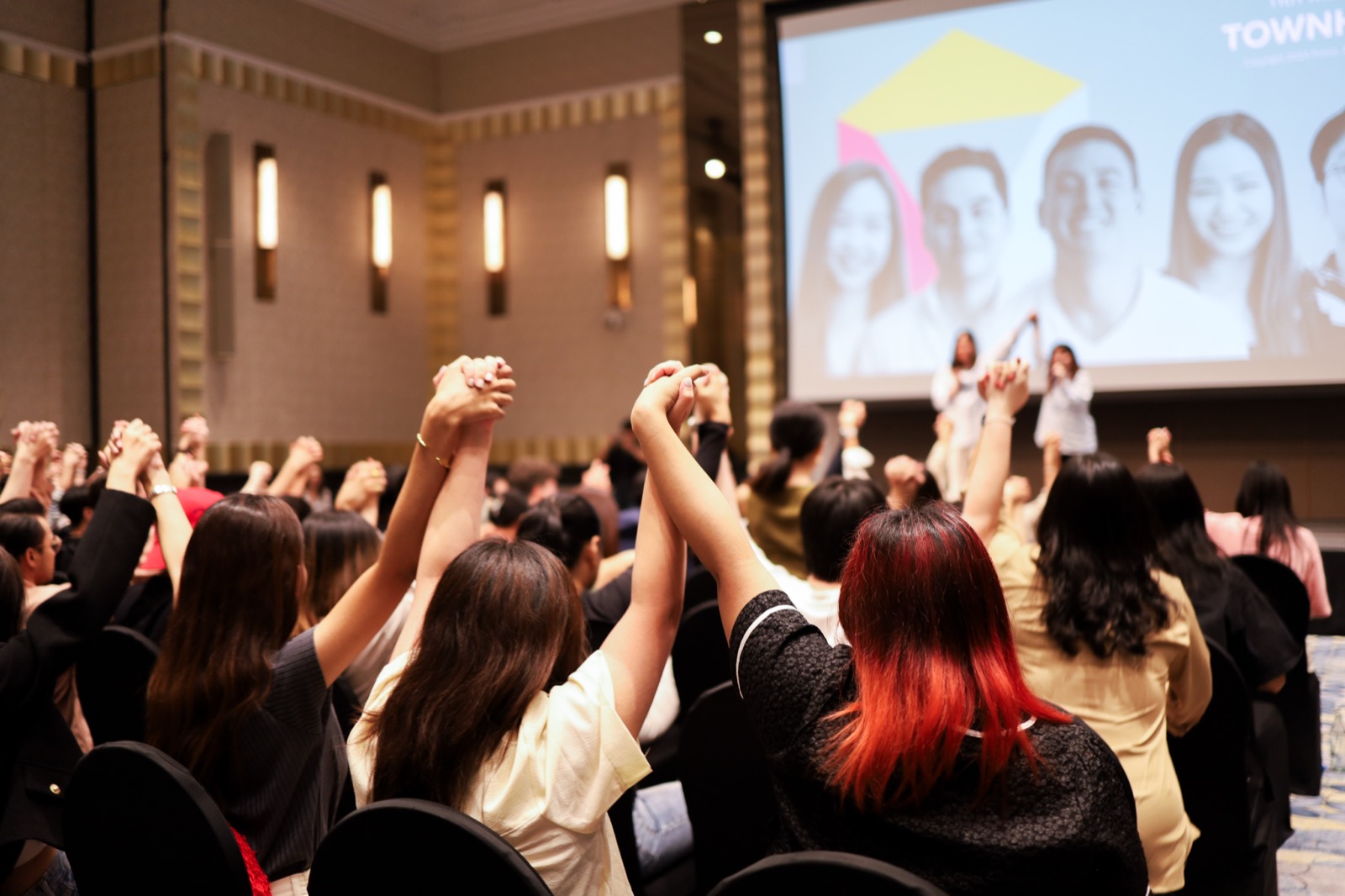 Attendees raising joined hands above their heads at an awards ceremony