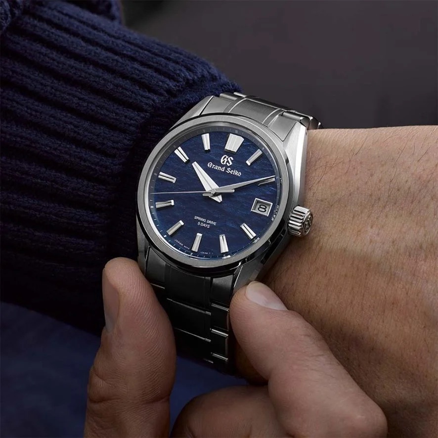 A Grand Seiko wristwatch with a blue dial, worn on a wrist