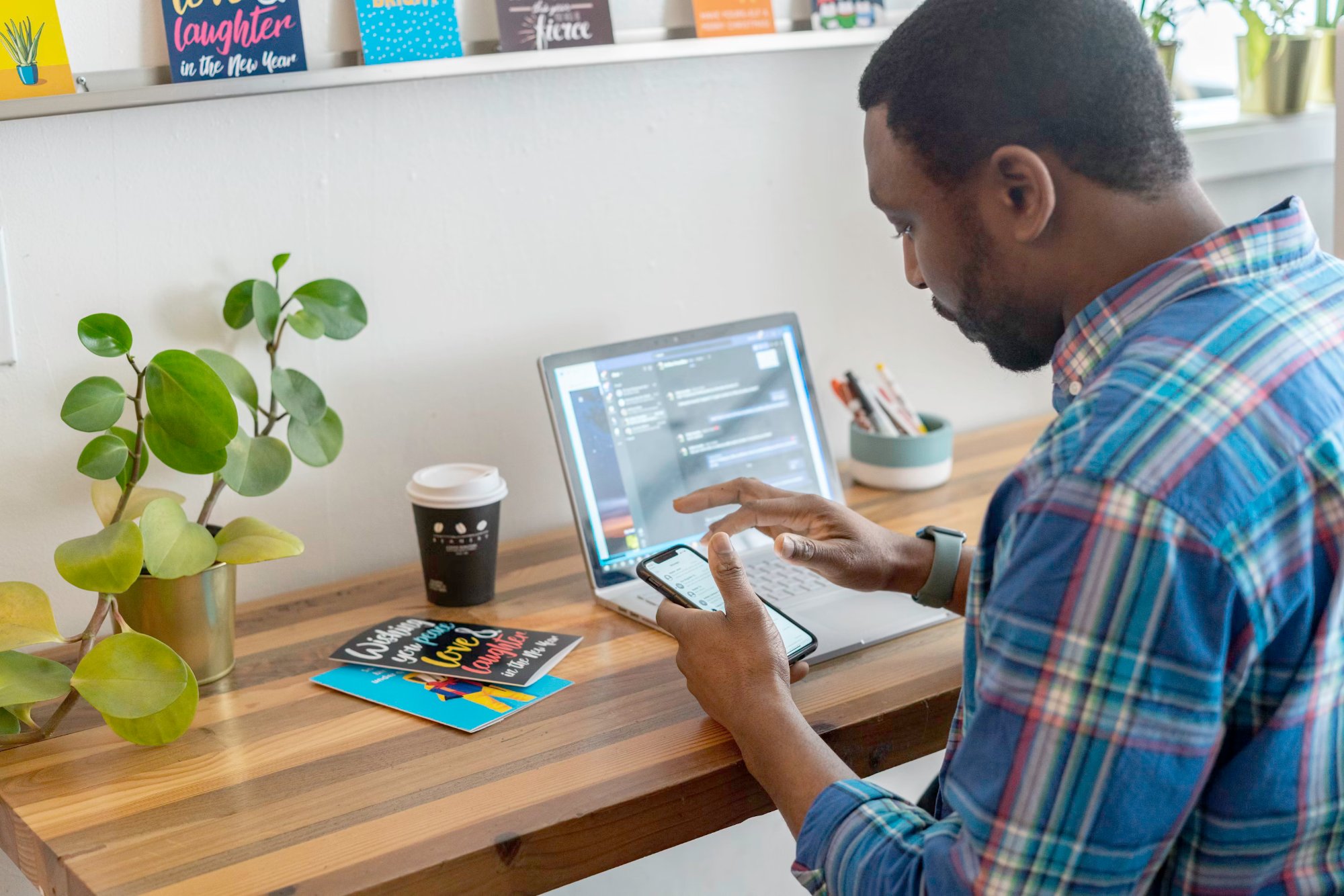 A person working through documentation across a laptop and phone at a desk