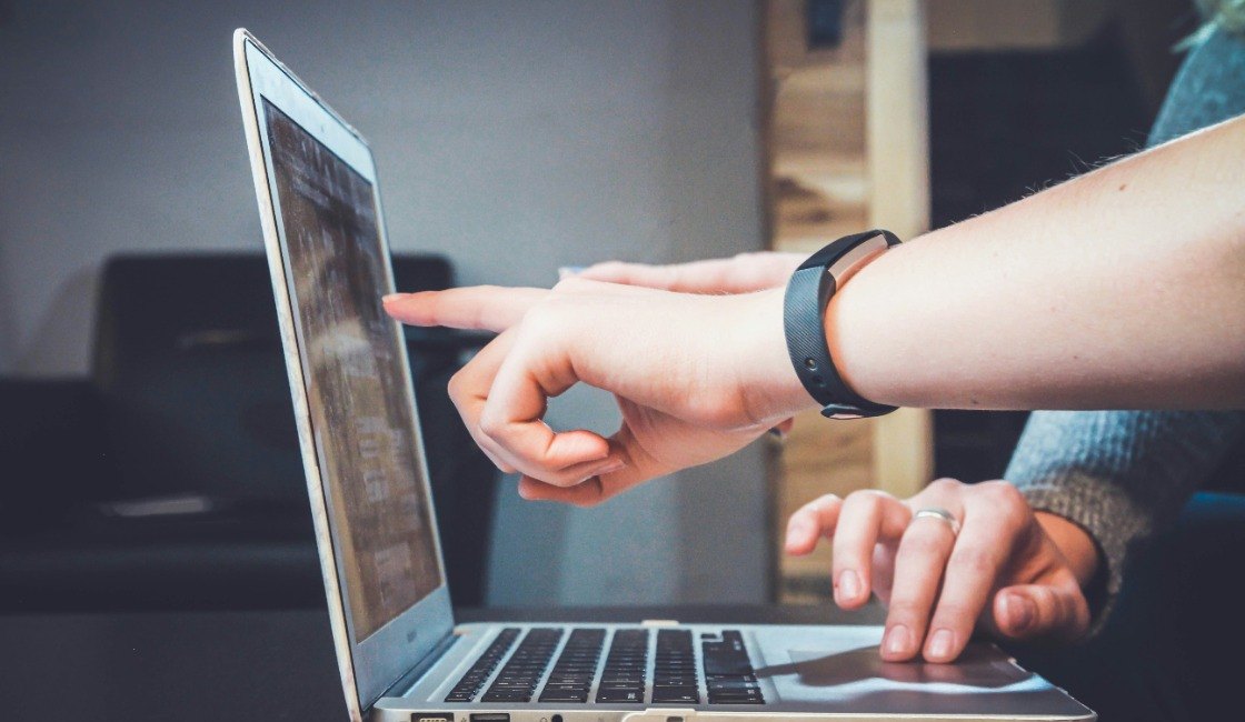 Two colleagues pointing at a laptop screen while reviewing page performance